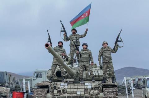 A tank bearing the name of National Hero of Azerbaijan Albert Agarunov with infantrymen heading into battle